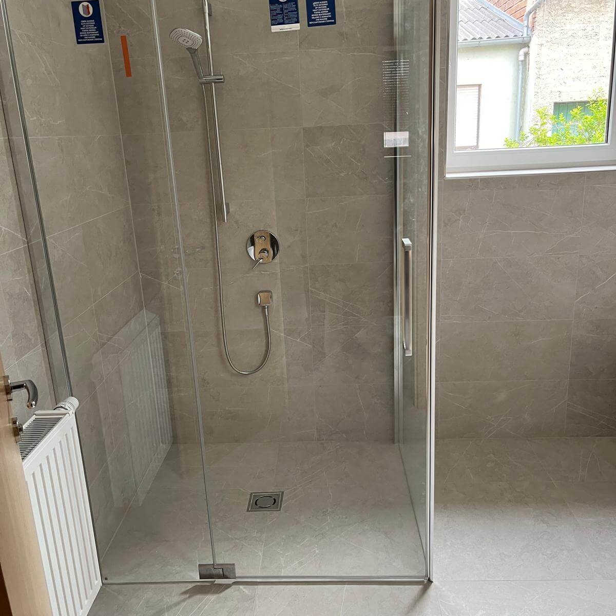 Begehbare Dusche mit Glasabtrennung, Regendusche und Fliesen in Natursteinoptik – Design-Bad in Bruck an der Leitha von Ihrem EMA Installateur. 