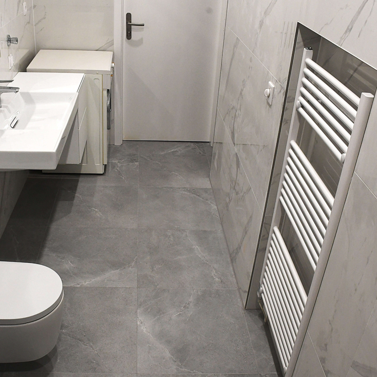 Bodenebene Dusche mit Haltegriffen und modernem Handtuchheizkörper: Sicherheit und Wärme im altersgerechten Bad durch Ihren EMA Installateur in 1230 Wien. 