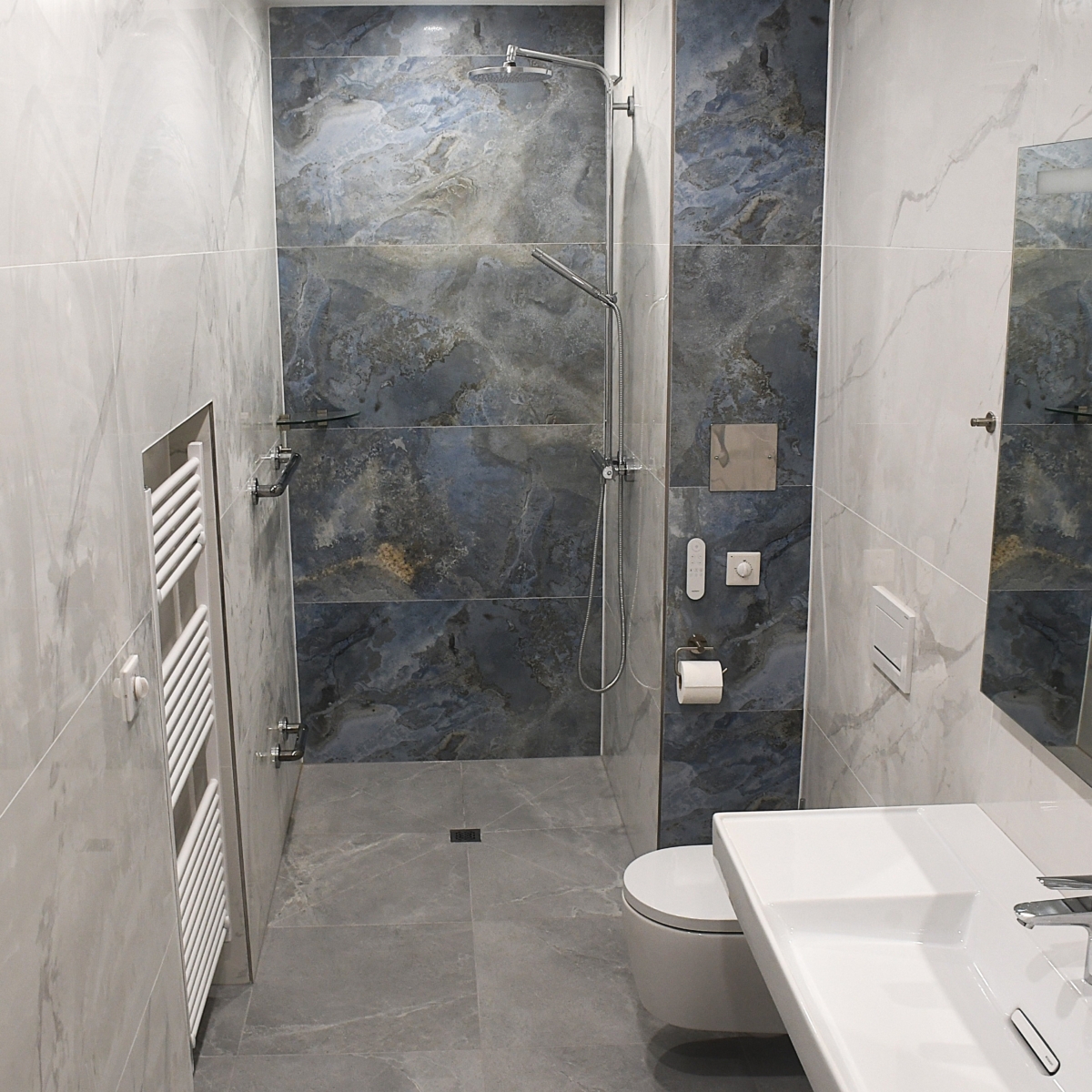 Ansicht der modernen, bodengleichen Dusche mit blauen Marmor-Akzentfliesen.